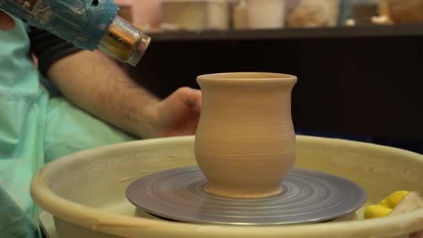 El alfarero trabaja en una rueda de cerámica. Cuencos de arcilla hechos de arcilla de color suave — Vídeo de stock