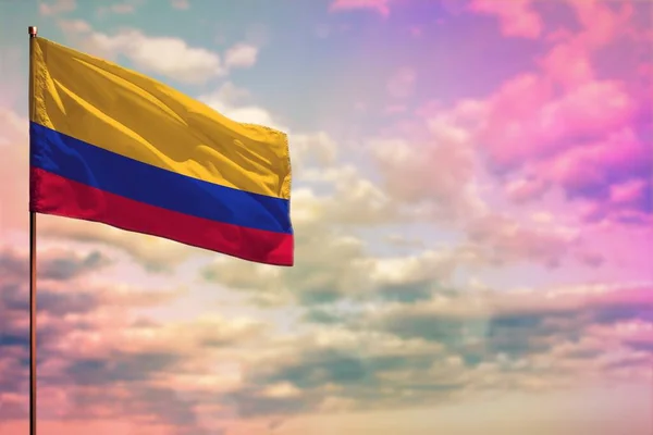 カラフルな曇りの空の背景にあなたのテキストのための場所とコロンビアの旗のモックアップをなびかせ — ストック写真