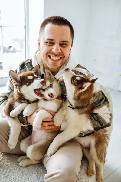 Adam kameraya hırlıyor ve dişlerini gösteriyor. Avrupalı bir adam kucağında bir sürü köpek yavrusu tutuyor. Ev atmosferi köpek yavrularıyla oynuyor. Yavru köpekler sahiplerinin kollarında oynaşıyorlar.