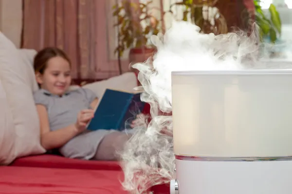 Girl reading book on the background of humidifier — Stock Photo, Image