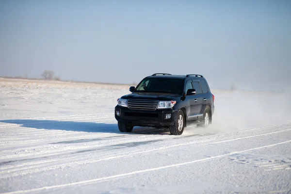 Black car traveling in the snow — Stock Photo, Image