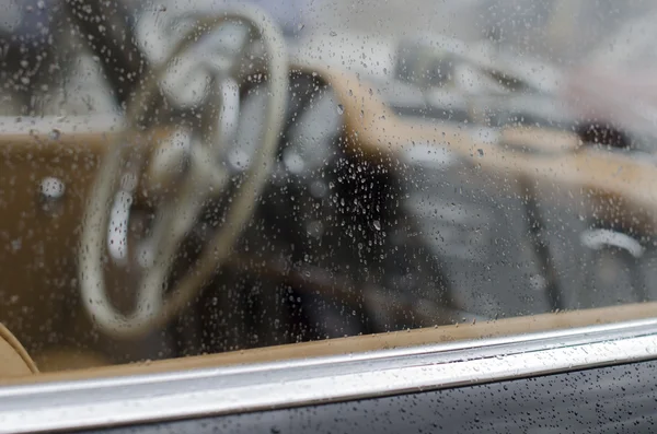 Dashboard of a classic car behind a rainy window — Stock Photo, Image