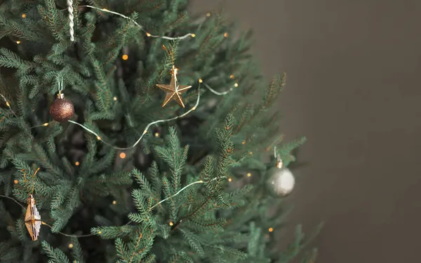 Gri arka planda oyuncaklar ve ışıklarla süslenmiş son moda minimalist yeşil Noel ağacı. Boşluğu kopyala.