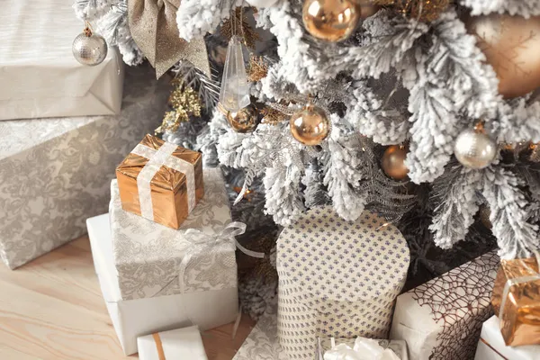 Kerstcadeautjes onder een luxe rijk versierde besneeuwde boom in pastelkleuren — Stockfoto