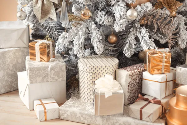 Regali di Natale sotto un albero di lusso ricco di decorazioni innevate in colori pastello Foto Stock