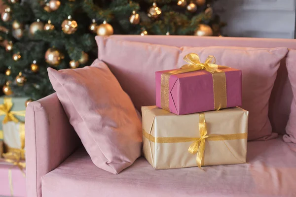 Nahaufnahme Foto viele Geschenkboxen im Zimmer Interieur mit einer Samtcouch, schwarzen modernen Kamin und wunderschönen geschmückten Weihnachtsbaum mit in der Lounge mit Geschenken in Gold, hellgrün und rosa Farbe — Stockfoto