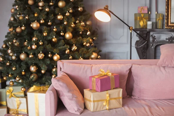 Flur Zimmer Mode Interieur mit einer Samtcouch, schwarzen modernen Kamin und wunderschönen geschmückten Weihnachtsbaum mit vielen Geschenkboxen in der Lounge mit Geschenken in Gold, Hellgrün und Rosa — Stockfoto