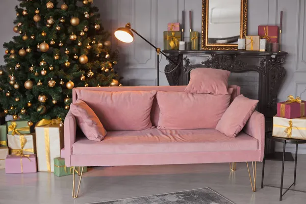 Hal kamer mode interieur met een fluwelen bank, zwarte moderne open haard en prachtige versierde kerstboom met veel geschenkdozen in de lounge met geschenken in goud, licht groen en roze kleur — Stockfoto