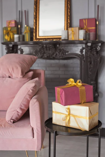 Hal kamer mode interieur met een fluwelen bank, zwarte moderne open haard en prachtige vele geschenkdozen. Grote stijlvolle design lounge met cadeautjes in goud, lichtgroen en roze kleur. — Stockfoto