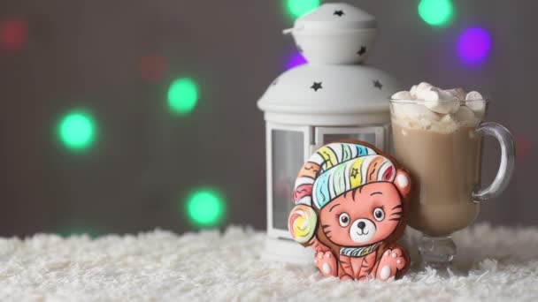 Mysig vinter semester bakgrund med pepparkakor tiger - symbol för det nya året 2022 med kopp kaffe med marshmallows ovanför de färgglada bokeh lampor. Kopiera utrymme. — Stockvideo