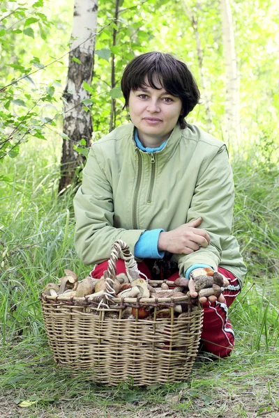 Flickan i skogen bredvid en korg med svamp — Stockfoto