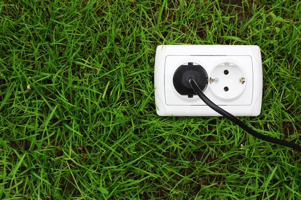 Electric power receptacle on a green grass background — Stock Photo, Image