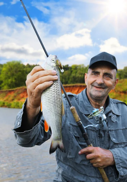 Chub en la mano del pescador contra el cielo y el río — Foto de Stock