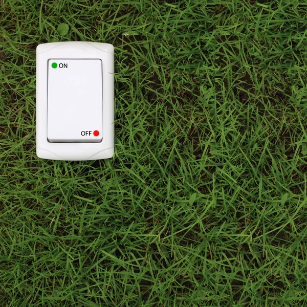Interruttore di alimentazione elettrica su uno sfondo verde erba — Foto Stock