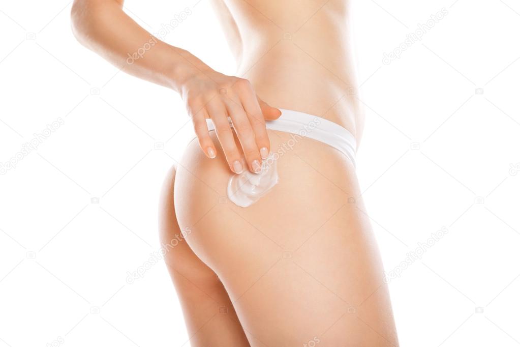 Woman applying moisturizer cream on legs isolated