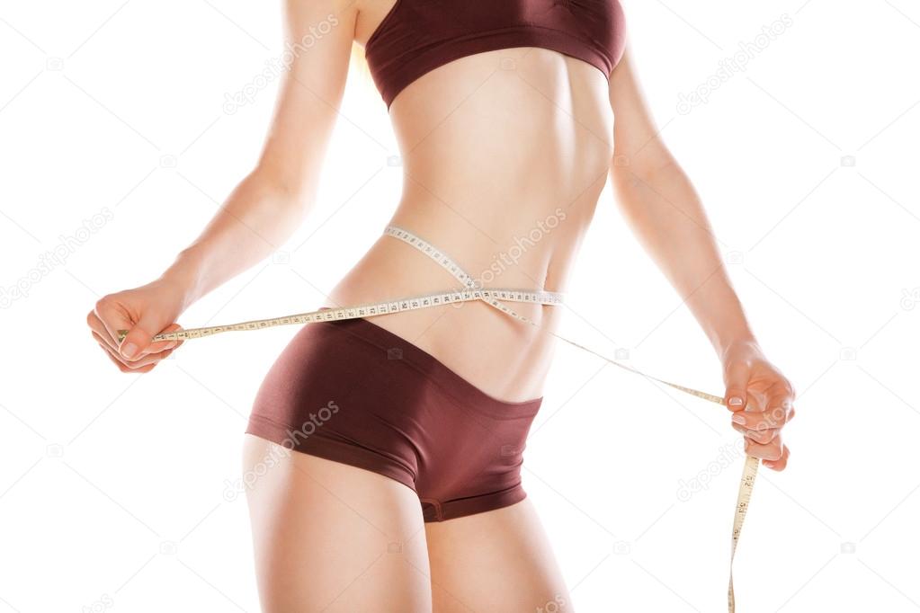 Athletic woman measuring her waist by metric tape