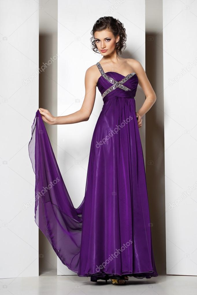 Young beautiful brunette in purple dress on white