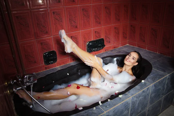 Beautiful woman relaxing in black tub with foam — Stock Photo, Image