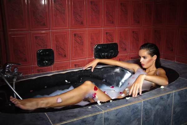 Beautiful woman relaxing in black tub with foam — Stock Photo, Image
