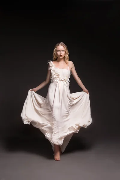 Dancing girl in wedding dress over dark background — Stock Photo, Image