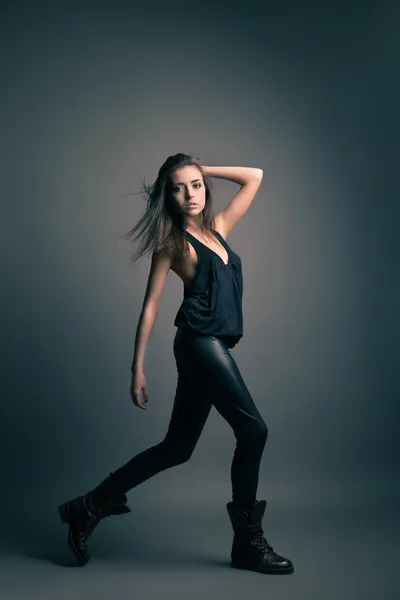 Модна модель в шкіряних штанях позує на сірому — стокове фото