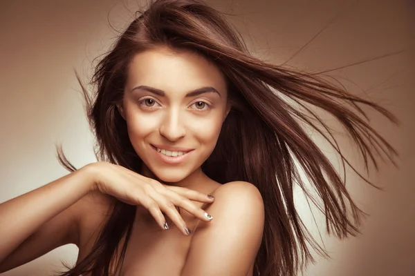 Atraktivní usmívající se žena s dlouhými vlasy na grey — Stock fotografie