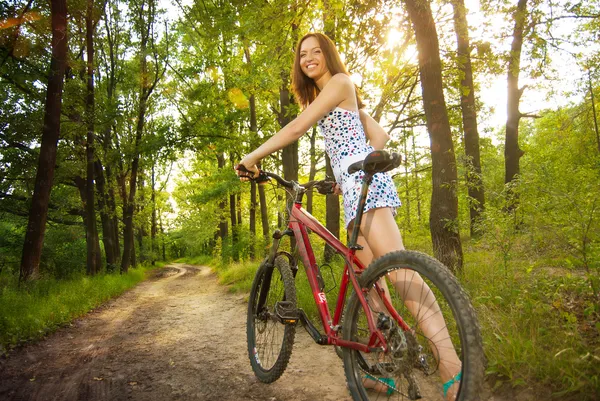 Bella giovane donna con bicicletta in un parco sorridente — Foto Stock