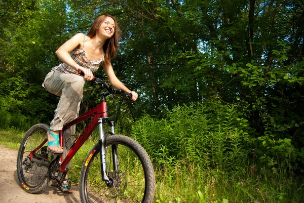 Bella giovane donna con bicicletta in un parco sorridente — Foto Stock