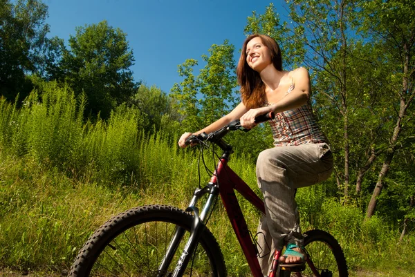 Bella giovane donna con bicicletta in un parco sorridente — Foto Stock