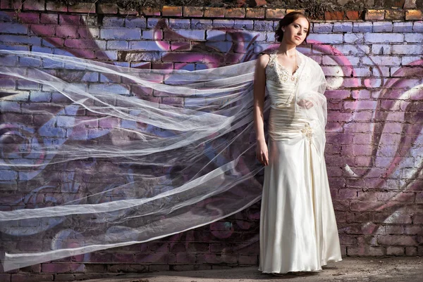 Bruid permanent in de buurt van kleurrijke muur met vliegende sluier — Stockfoto