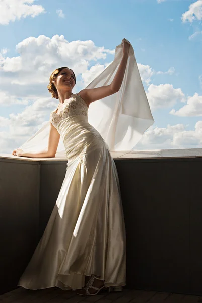 Happy beautiful bride with flying fabric over sky — Stock Photo, Image