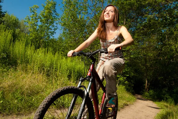 Bella giovane donna con bicicletta in un parco sorridente — Foto Stock