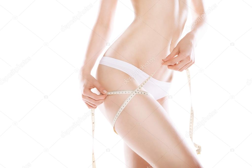 Slimming woman measuring thigh with tape