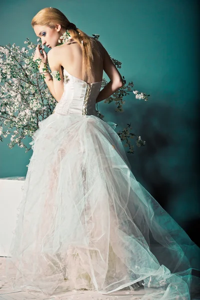 Noiva em vestido de noiva atrás do arbusto com flores — Fotografia de Stock