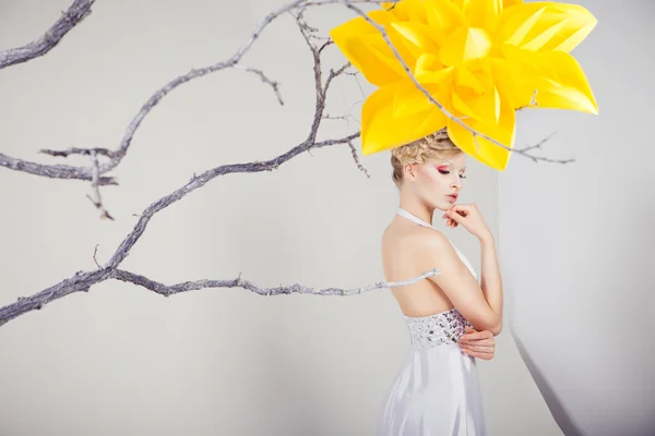 Blond kvinna i vit klänning med stor gul blomma — Stockfoto