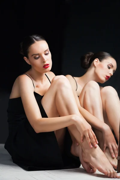 Kvinnan bryr sig benen nära spegeln över svart — Stockfoto