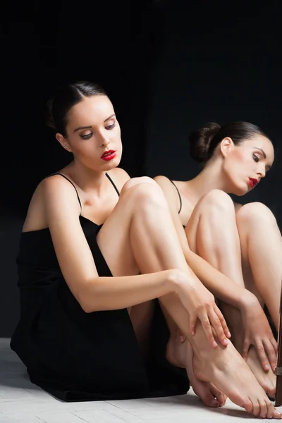 Woman cares her legs near mirror over black Stock Picture