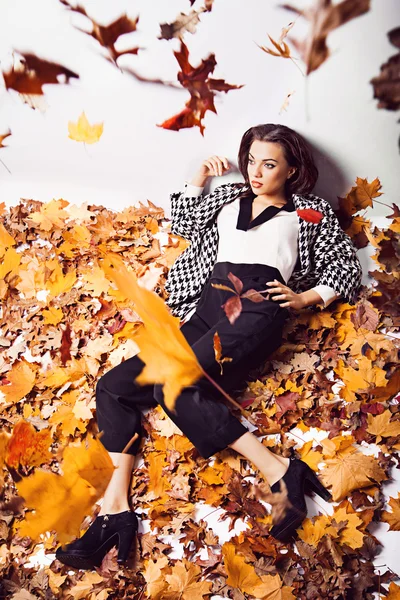 Mujer morena retrato en hojas de otoño acostado —  Fotos de Stock