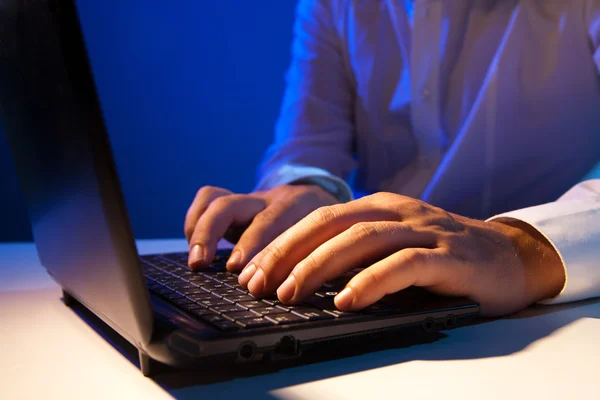 Businessman working on laptop over dark — Stock Photo, Image