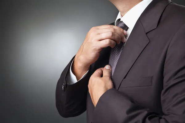 Empresário em traje preto amarrar um 's necktie — Fotografia de Stock