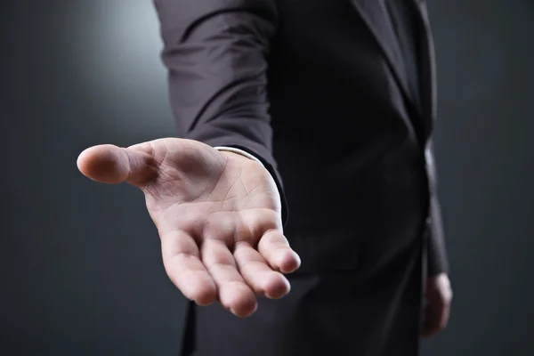 Hombre de negocios con la mano vacía sobre fondo oscuro — Foto de Stock