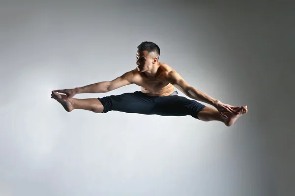 Homem caucasiano ginástica postura salto no cinza — Fotografia de Stock