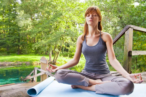 Chica joven haciendo yoga (pose de loto) en el parque — Foto de Stock