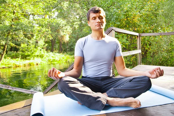 Joven haciendo yoga (pose de loto) en el parque — Foto de Stock