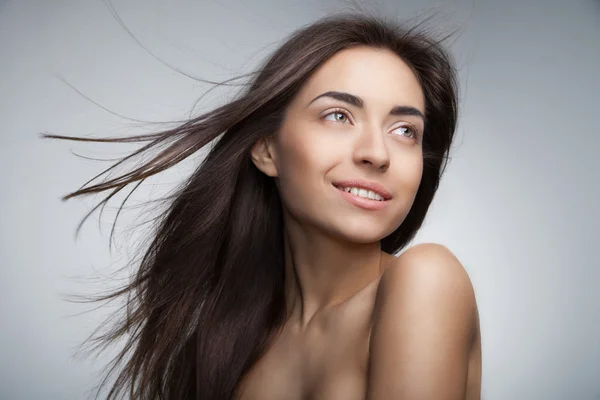 Atrakcyjny uśmiechający się kobieta z długimi włosami na szary — Zdjęcie stockowe