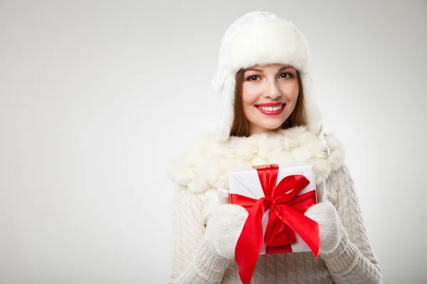 Smiling woman with gift box over light background — Stock Photo, Image