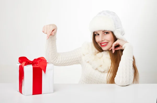 Smiling woman with gift box over light background — Stock Photo, Image