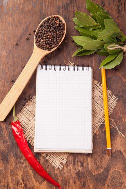 kaşıklar, ahşap arka plan üstünde defter içinde baharatlar