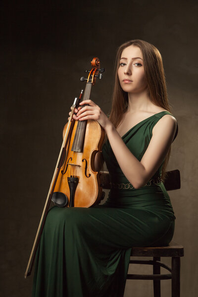 Beautiful young woman playing violin over black