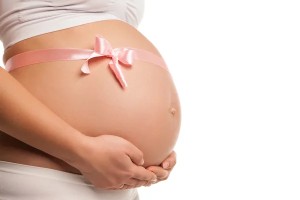 Schwangerer Bauch mit rosa Schleife über weißem — Stockfoto